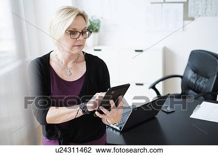 Stock Image - Businesswoman using tablet in office. Fotosearch