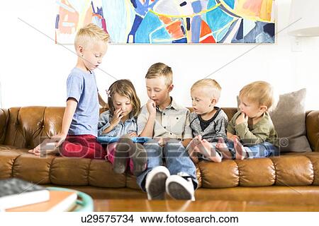Children (2-3, 4-5, 6-7) sitting on sofa and using digital tablet View Large Photo Image Picture - Children (2-3, 4-5, 6-7) sitting on sofa and using digital tablet. Fotosearch