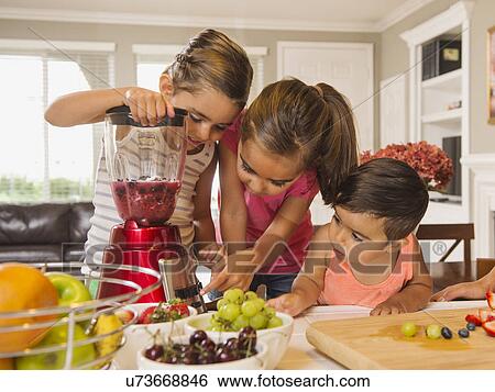 Stock Photograph - Children (2-3, 6-7, 8-9) preparing fruit cocktails. Fotosearch