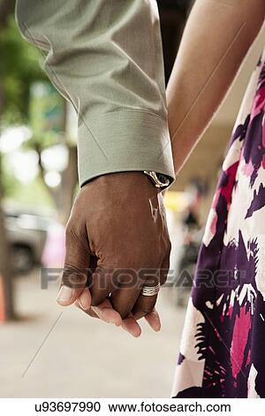Stock Image - Close up of couple holding hands. Fotosearch