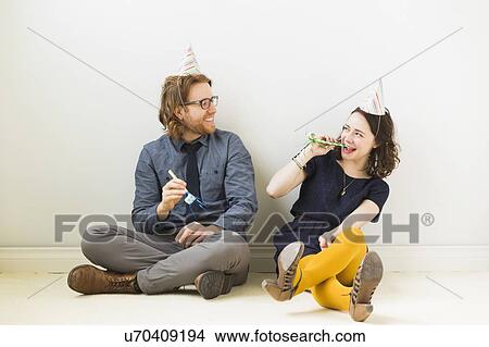 Couple with party horn blowers and party hats sitting on floor View Large Photo Image Picture - Couple with party horn blowers and party hats sitting on floor. Fotosearch