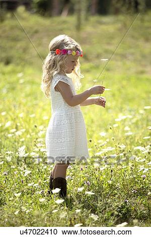 Stock Image - Cute girl (4-5) in white dress standing in meadow. Fotosearch