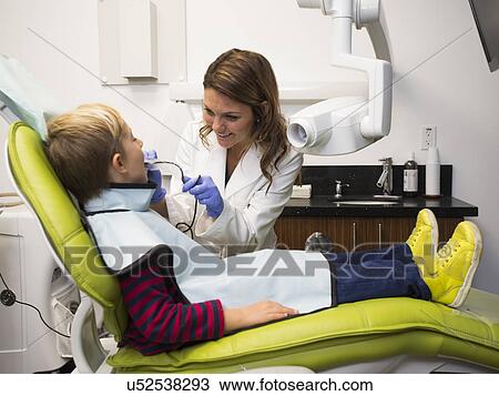 Stock Image - Dentist and patient (8-9) in dentist's office. Fotosearch