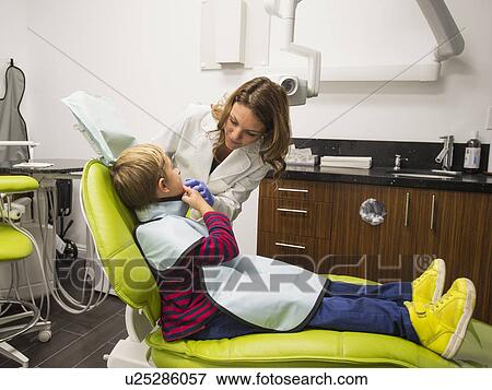 Stock Photo - Dentist and patient (8-9) in dentist's office. Fotosearch