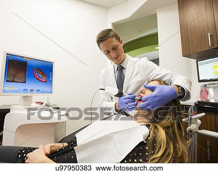 Stock Image - Dentist and patient in dentist's office. Fotosearch