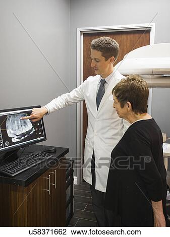 Stock Image - Dentist showing patient x-ray on computer screen. Fotosearch