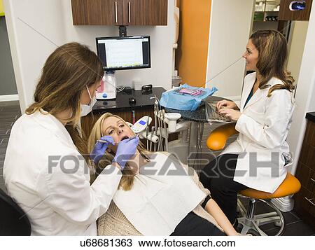 Stock Image - Dentists and patient in dentist's office. Fotosearch