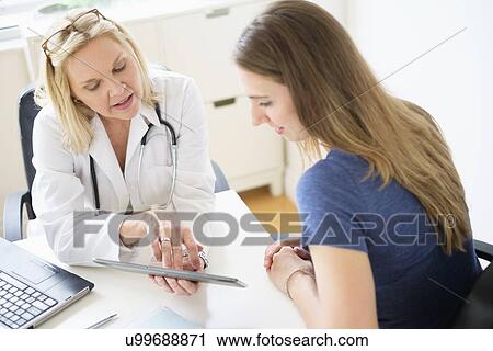 Stock Image - Doctor talking to patient in office. Fotosearch