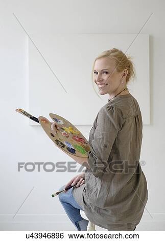 Stock Photograph - Female artist painting in studio. Fotosearch