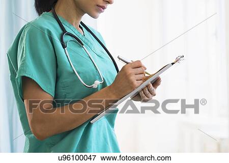 Stock Photo - Female doctor making notes. Fotosearch