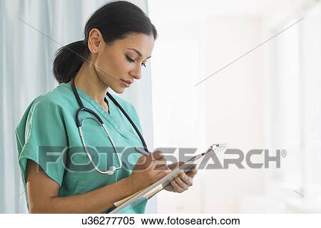 Stock Photography - Female doctor making notes. Fotosearch