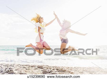 Female friends jumping on beach View Large Photo Image Stock Image - Female friends jumping on beach. Fotosearch