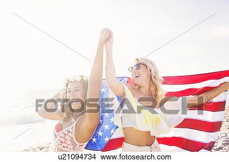 Picture - Female friends on beach with American flag. Fotosearch