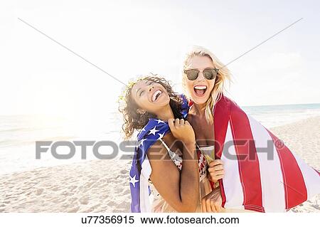 Stock Photography - Female friends on beach with American flag. Fotosearch