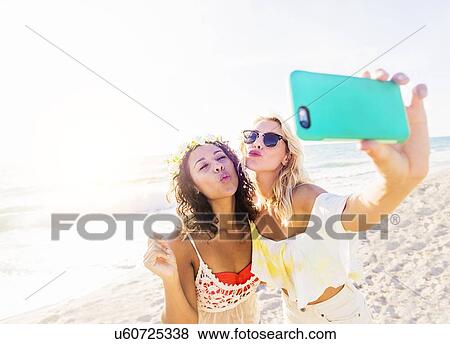 Stock Photo - Female friends taking selfie on beach. Fotosearch