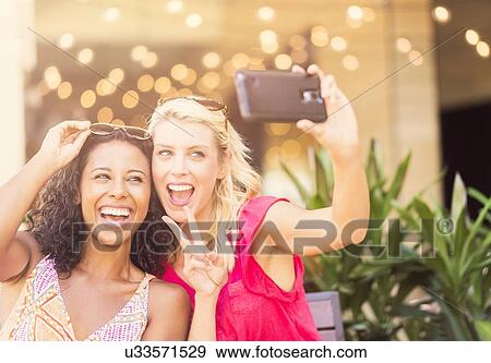 Female friends taking selfie with smart phone in cafe View Large Photo Image Stock Photo - Female friends taking selfie with smart phone in cafe. Fotosearch