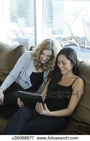Stock Photo - Female friends watching tablet. Fotosearch