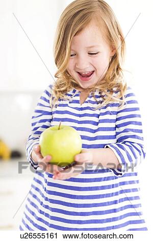 Girl (4-5) looking at apples, laughing View Large Photo Image Stock Image - Girl (4-5) looking at apples, laughing. Fotosearch