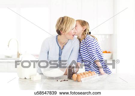 Stock Photo - Girl (4-5) whispering into mom's ear. Fotosearch