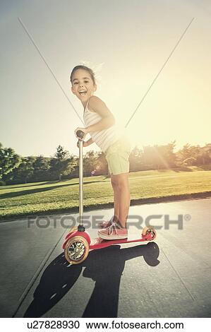 Stock Image - Girl (6-7) playing in park. Fotosearch