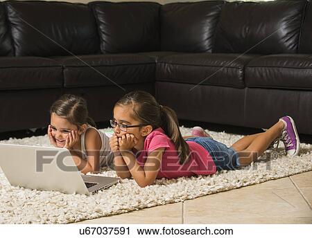 Stock Image - Girls (6-7, 8-9) using laptop at home. Fotosearch