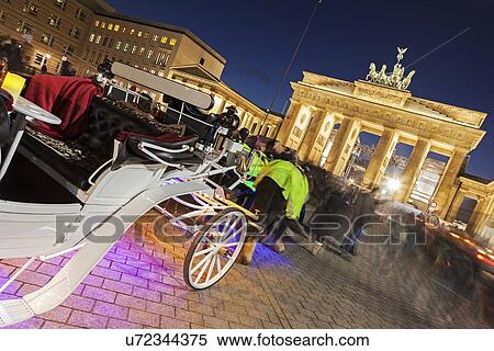 Stock Photography - Horse carts in front of illuminated Brandenburg Gate. Fotosearch