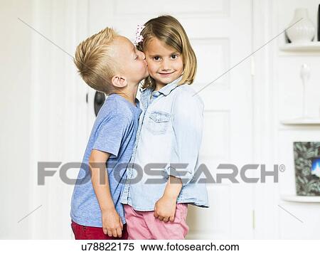 Stock Photography - Little boy (4-5) kissing sister (4-5) . Fotosearch