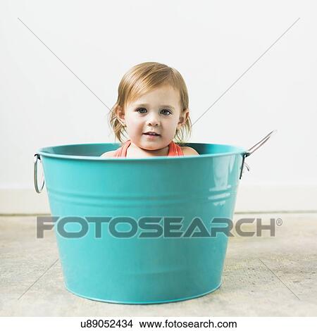 Picture - Little girl (2-3) sitting in turquoise bucket. Fotosearch