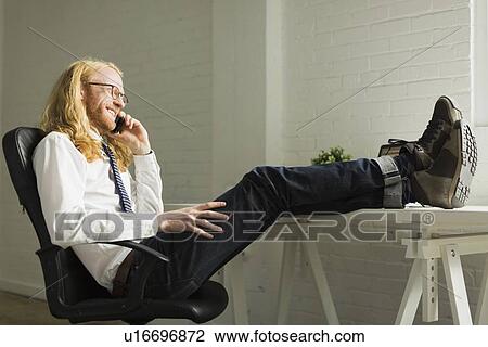 Man talking on phone with feet up on desk View Large Photo Image Stock Image - Man talking on phone with feet up on desk. Fotosearch