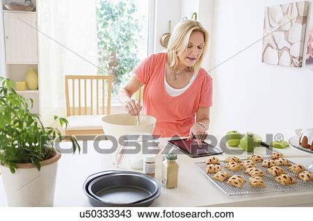 Stock Image - Mature woman baking in kitchen. Fotosearch