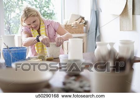 Stock Photo - Mature woman making pottery in studio. Fotosearch