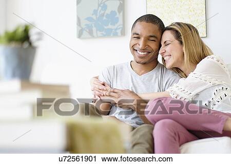Stock Image - Mid adult couple embracing in living room. Fotosearch