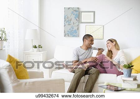 Mid adult couple relaxing in living room View Large Photo Image Picture - Mid adult couple relaxing in living room. Fotosearch