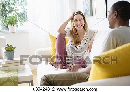 Stock Image - Mid adult couple relaxing in living room. Fotosearch