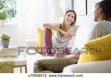 Mid adult couple relaxing in living room View Large Photo Image Stock Photography - Mid adult couple relaxing in living room. Fotosearch