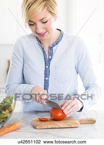 Stock Image - Mid-adult woman preparing salad. Fotosearch