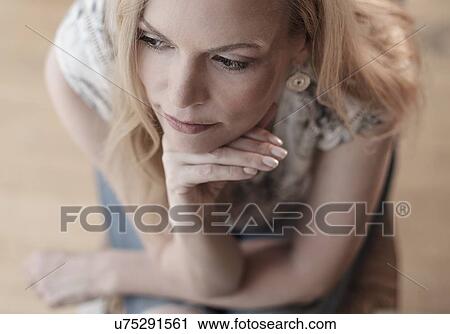 Mid-adult woman sitting on chair, thinking View Large Photo Image Stock Image - Mid-adult woman sitting on chair, thinking. Fotosearch