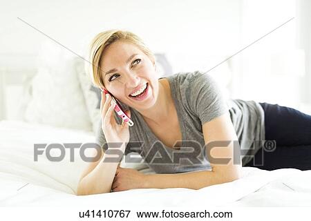 Stock Photo - Mid-adult woman talking on phone in bedroom. Fotosearch