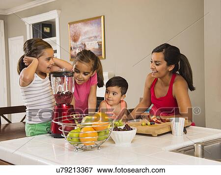 Stock Photo - Mother and children (2-3, 6-7, 8-9) preparing fruit cocktails. Fotosearch