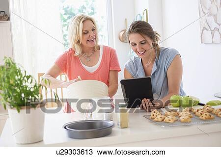Stock Image - Mother with adult daughter baking in kitchen. Fotosearch