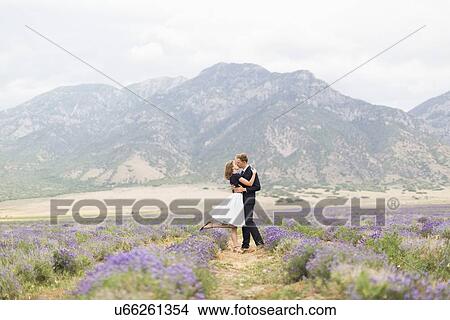 Picture - Newlywed couple kissing in lavender field with mountains on background. Fotosearch
