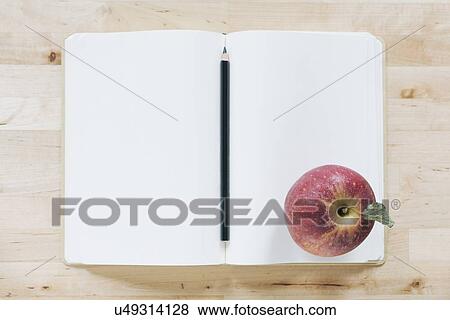 Stock Photo - Overhead view of pencil and apple in notebook. Fotosearch