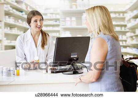 Picture - Patient talking to pharmacist in pharmacy. Fotosearch
