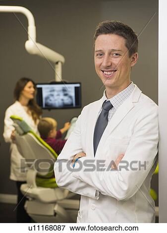 Portrait of dentist with colleague and patient (8-9) in background View Large Photo Image Stock Photo - Portrait of dentist with colleague and patient (8-9) in background. Fotosearch