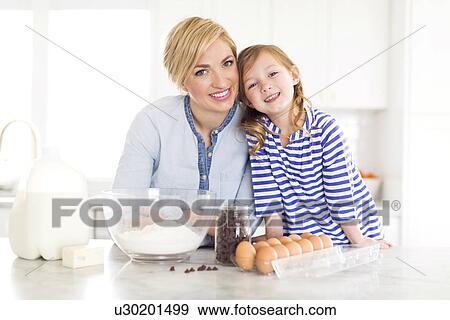 Portrait of girl (4-5) spending time with mom in kitchen View Large Photo Image Stock Photo - Portrait of girl (4-5) spending time with mom in kitchen. Fotosearch