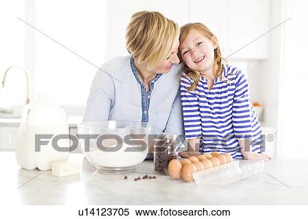 Stock Photography - Portrait of girl (4-5) spending time with mom in kitchen. Fotosearch