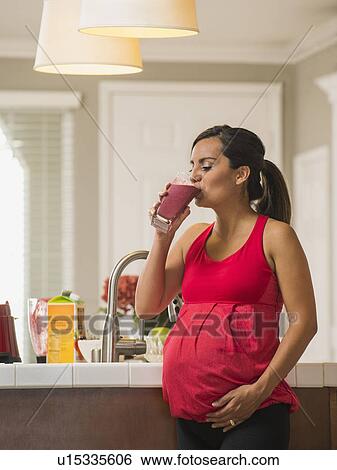 Stock Photograph - Portrait of pregnant woman drinking fruit cocktail. Fotosearch
