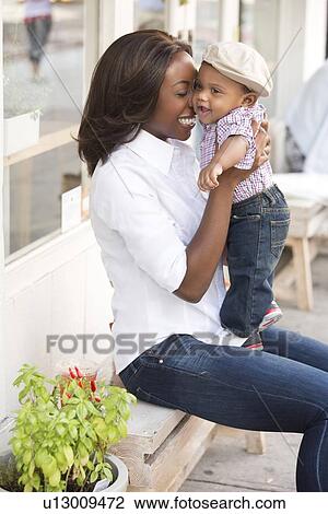 Stock Image - Portrait of smiling woman holding son (12-17 months). Fotosearch