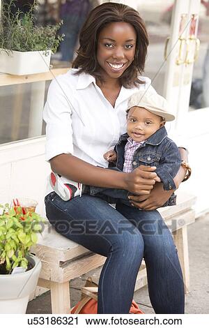 Stock Image - Portrait of smiling woman holding son (12-17 months). Fotosearch