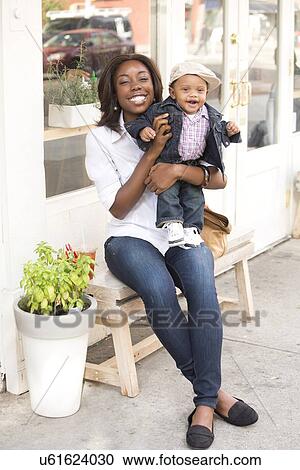 Stock Image - Portrait of smiling woman holding son (12-17 months). Fotosearch